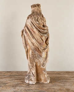 Back view of a French Antique Madonna, crowned with roses and standing with her gaze gently lowered and one hand resting across her chest. Deeply folded robes and a sweeping mantle give the figure a graceful, sculptural presence, with carved detail continuing around the back.