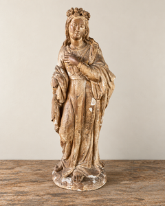 An expressive carved wooden French Antique Madonna, with a crown of roses and standing with her gaze gently lowered and one hand resting across her chest. Deeply folded robes and a sweeping mantle give the figure a graceful, sculptural presence, with carved detail continuing around the back.