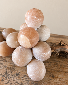 A detail of substantial vintage alabaster grape cluster, attributed to Italy, with softly rounded stone fruit gathered around a richly textured natural wooden stem. Muted shades of peach and smoky grey lend the piece a quiet, painterly quality