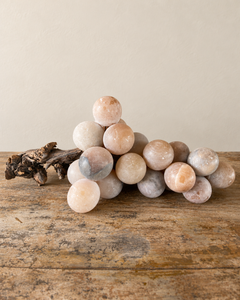 A substantial vintage alabaster grape cluster, attributed to Italy, with softly rounded stone fruit gathered around a richly textured natural wooden stem. Muted shades of peach and smoky grey lend the piece a quiet, painterly quality