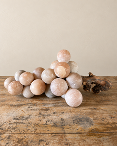 A substantial vintage alabaster grape cluster, attributed to Italy, with softly rounded stone fruit gathered around a richly textured natural wooden stem. Muted shades of peach and smoky grey lend the piece a quiet, painterly quality