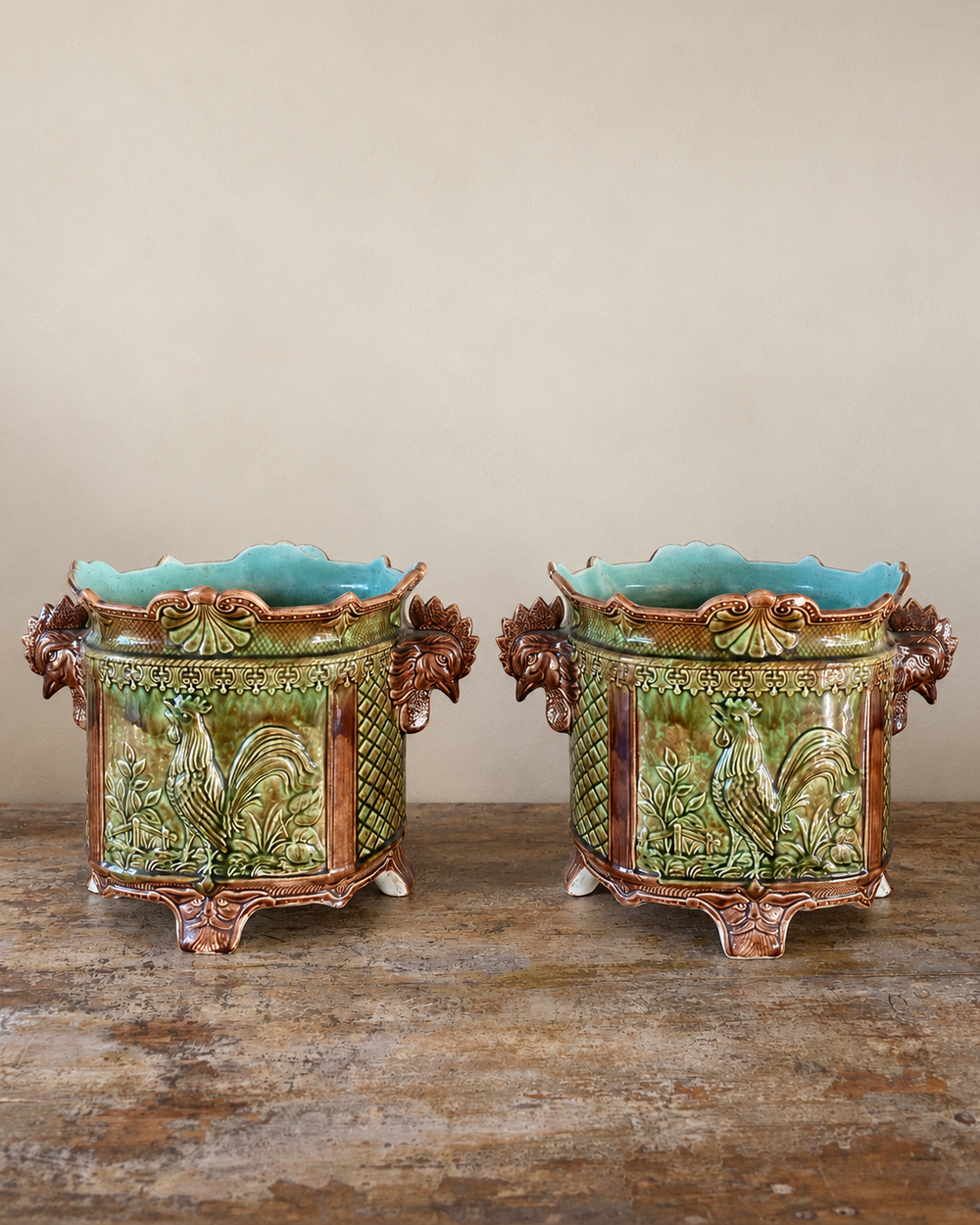 Pair of antique majolica cachepots with rooster-head handles, green and brown glaze and duck egg blue interiors.
