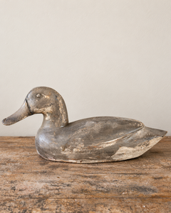 A beautifully sculptural vintage wooden duck, with a gently curved neck, rounded breast and long, tapering tail. Its simple carved features give it an endearing expression, while the low, elegant silhouette is particularly lovely in profile.