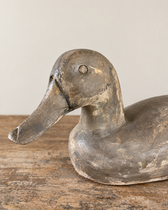 A head detail of a beautifully sculptural vintage wooden duck, with a gently curved neck, rounded breast and long, tapering tail. Its simple carved features give it an endearing expression, while the low, elegant silhouette is particularly lovely in profile.