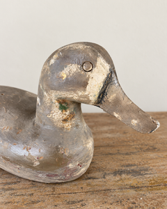A beautifully sculptural vintage wooden duck, with a gently curved neck, rounded breast and long, tapering tail. Its simple carved features give it an endearing expression, while the low, elegant silhouette is particularly lovely in profile.