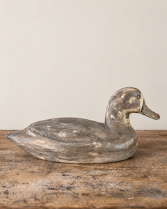 A beautifully sculptural vintage wooden duck, with a gently curved neck, rounded breast and long, tapering tail. Its simple carved features give it an endearing expression, while the low, elegant silhouette is particularly lovely in profile.